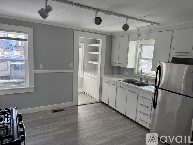 A kitchen with a refrigerator, sink, and cabinets.