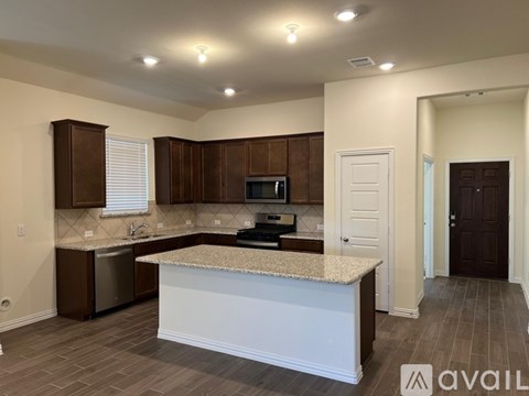 A kitchen with brown cabinets and a granite countertop.