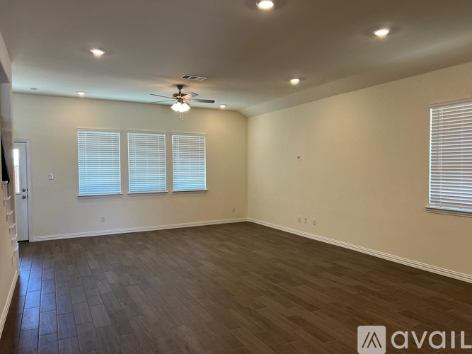 A spacious room with a ceiling fan and wooden flooring.