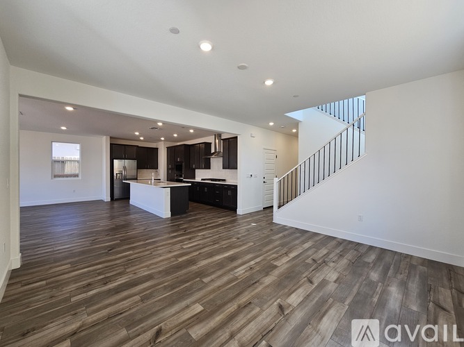 A spacious living room with wooden flooring and a staircase.