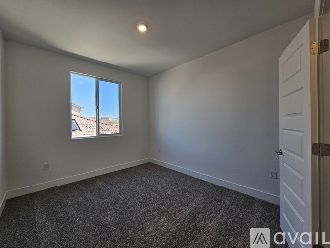 A room with a carpeted floor and a window overlooking a building.