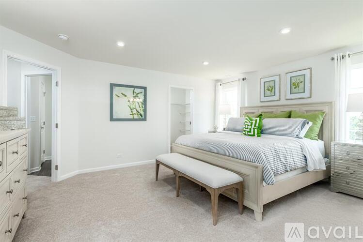 A bedroom with a bed, bench, and two pictures on the wall.