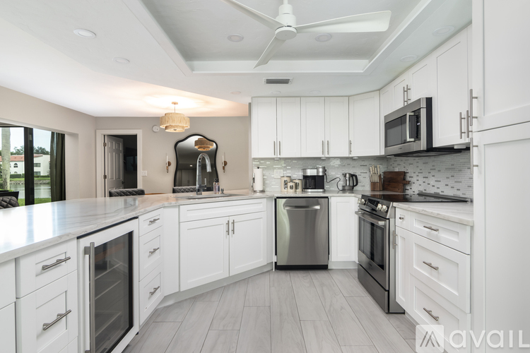 A modern kitchen with white cabinets and stainless steel appliances.