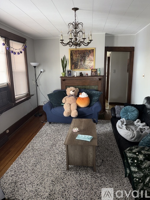 A living room with a blue couch and a teddy bear on the coffee table.