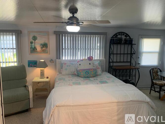 A bedroom with a bed, chair, and a fan.