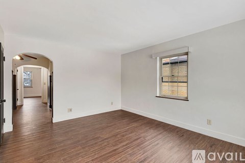 A spacious room with wooden floors and a window with blinds.