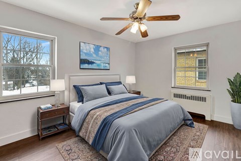 A bedroom with a bed, a ceiling fan, and a window with a view of a snowy landscape.