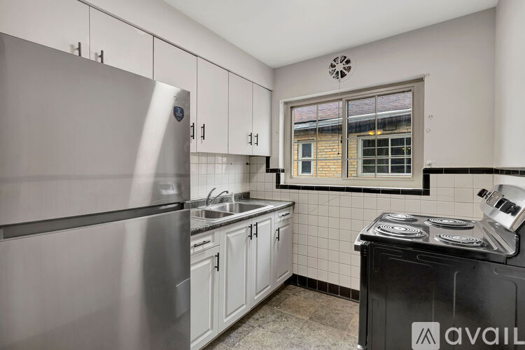 A kitchen with a stainless steel refrigerator and a black stove top oven.