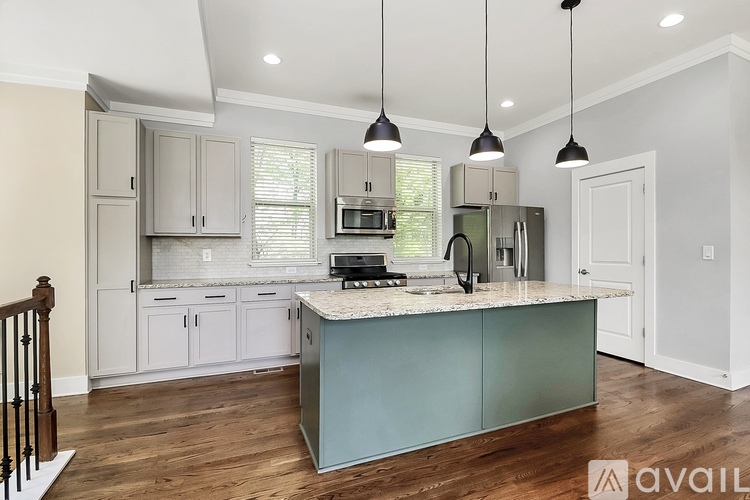 A kitchen with a large island and pendant lights.