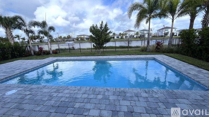 A pool surrounded by a brick patio and palm trees.