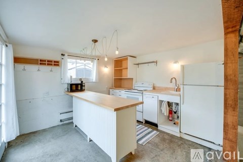A kitchen with a white fridge, dishwasher, and oven, with a wooden counter and a window with blinds.