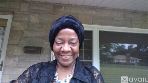 A woman wearing a black lace top and a black head wrap smiles at the camera.