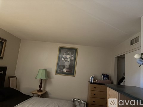 A bedroom with a bed, nightstand, and a painting on the wall.