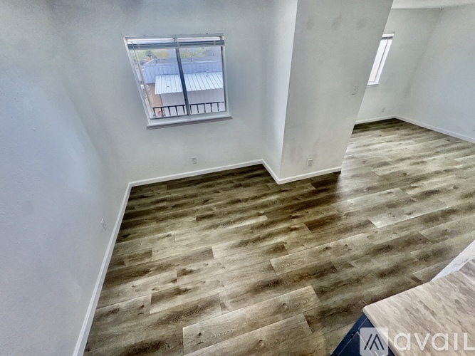 A room with wooden flooring and a window with a view of a fence and trees.