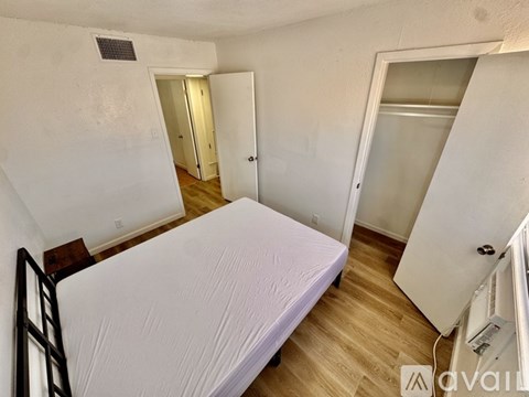 A room with wooden flooring and a window with a view of a fence and trees.