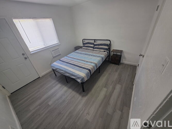 A bedroom with a bed, nightstand, and window.