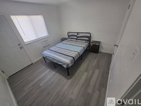 A bedroom with a bed, nightstand, and window.