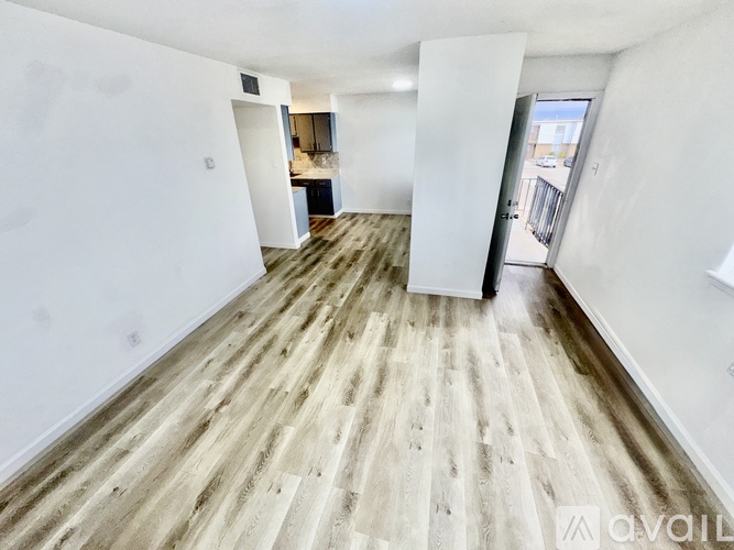 A spacious room with wooden flooring and white walls.