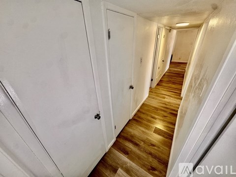 A spacious room with wooden flooring and white walls.
