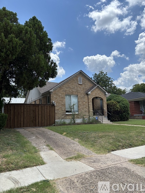 A house with a brown fence and a tree in front.