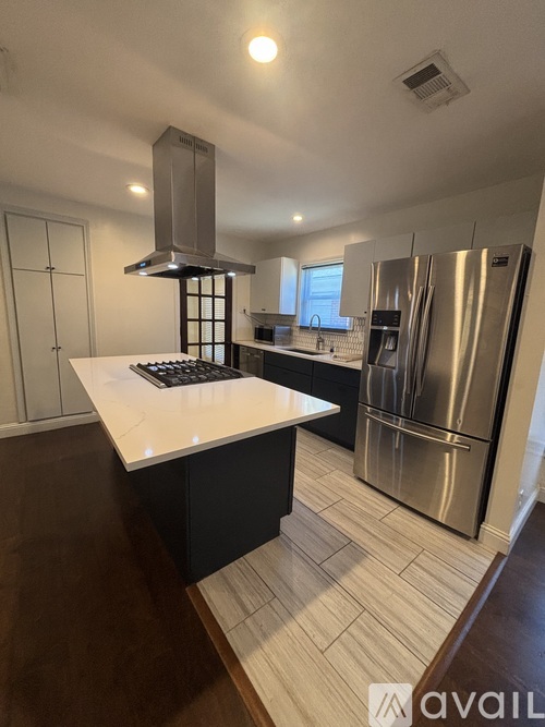 A kitchen with a white countertop and a stainless steel refrigerator.