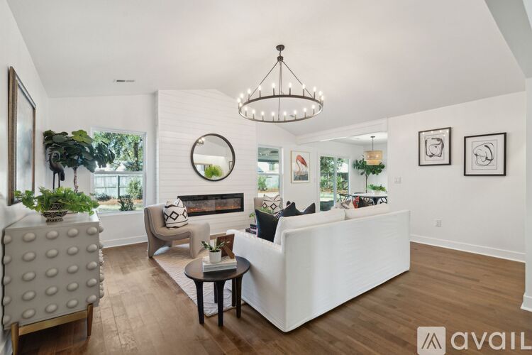 A living room with a white couch, a grey armchair, a coffee table, and a chandelier.