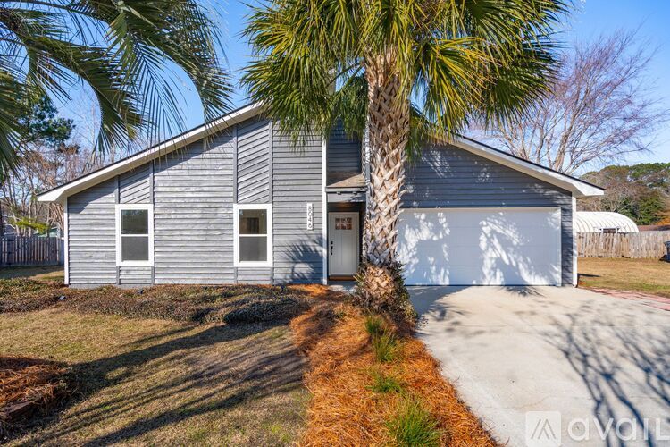 A house with a grey exterior and a palm tree in front.