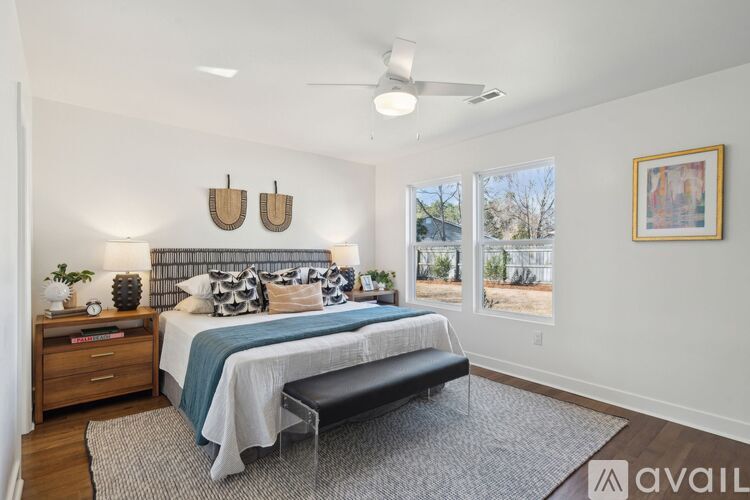 A bedroom with a bed, a bench, and a ceiling fan.