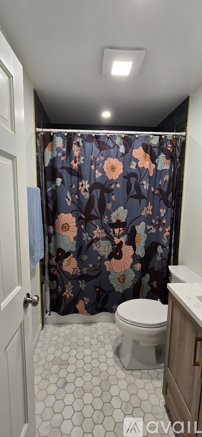 A bathroom with a floral shower curtain and a white toilet.