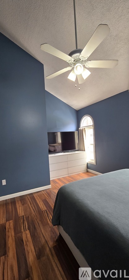 A bedroom with a bed and a ceiling fan.