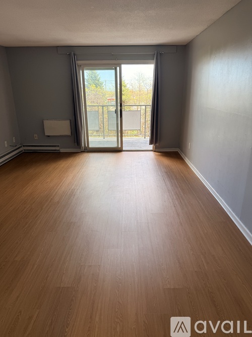 A room with wooden flooring and a sliding glass door leading outside.