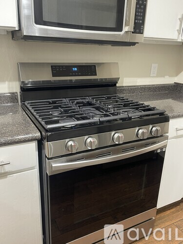 A modern kitchen with a stainless steel gas stove and microwave above it.