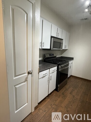A kitchen with white cabinets and a black countertop.