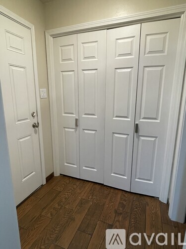 A white door with a silver handle is on the left and three white doors with silver handles are on the right.