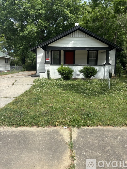 A small white house with a red door is for sale.