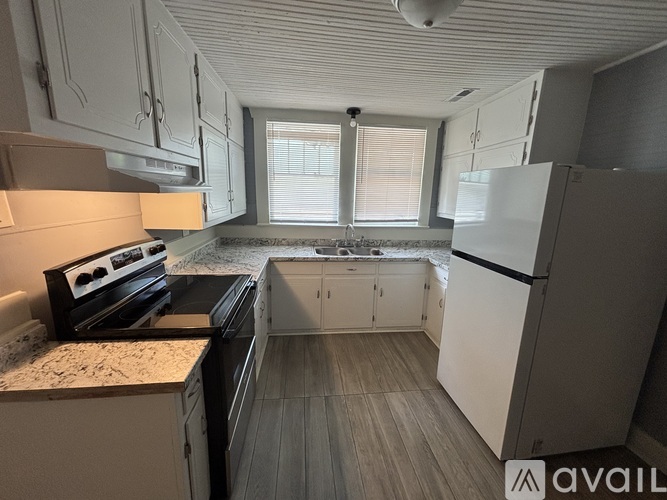 A kitchen with white cabinets and a black countertop.