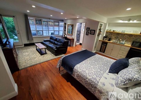 A bedroom with a patterned bedspread and a black sofa.