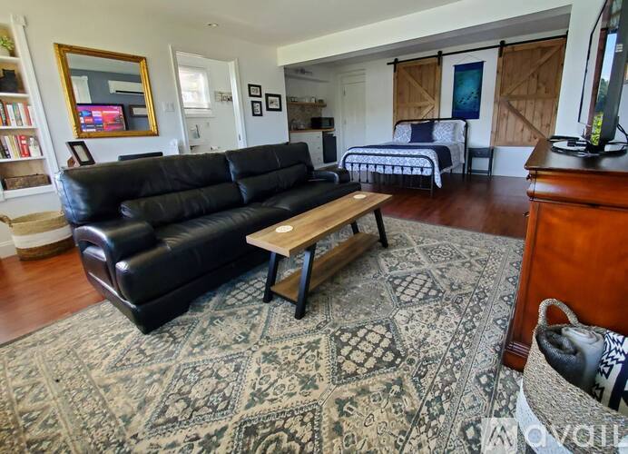 A black leather sofa sits in a living room with a rug on the floor.