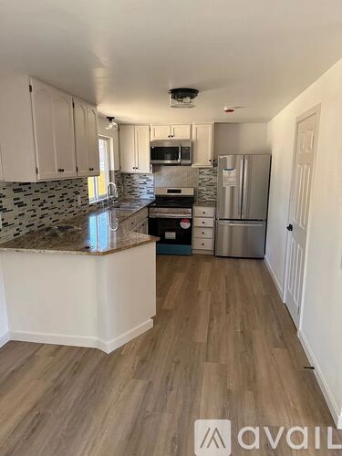 A kitchen with a granite countertop and wooden flooring.