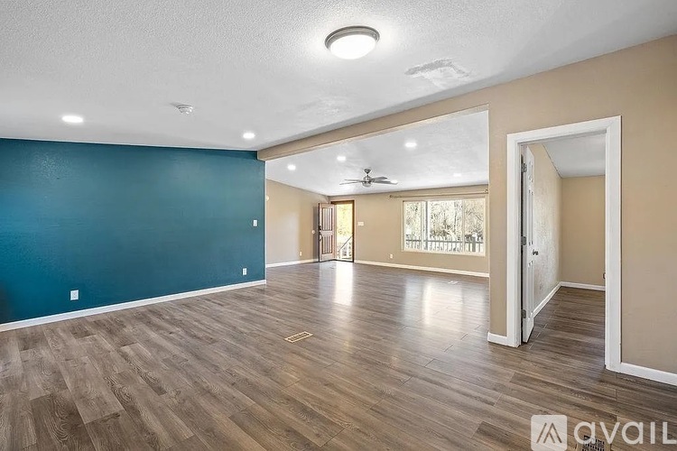 A spacious room with wooden flooring and a ceiling fan.
