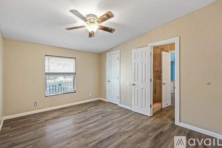 A room with a ceiling fan and a window with blinds.