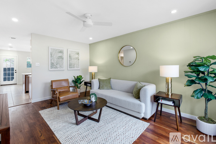 A living room with a white couch, a brown chair, a coffee table, and a plant.