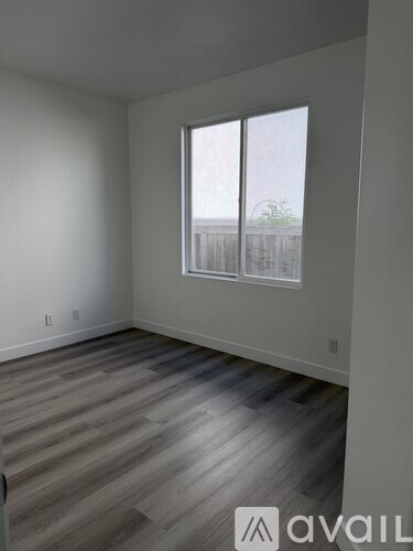 A room with a large window and wooden flooring.