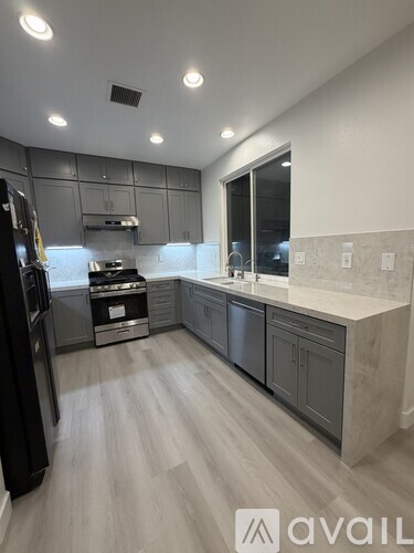 A modern kitchen with a black refrigerator and stove top oven.