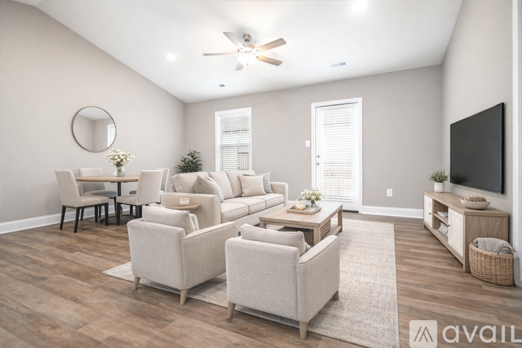 A living room with a white couch, a wooden coffee table, and a television on a stand.