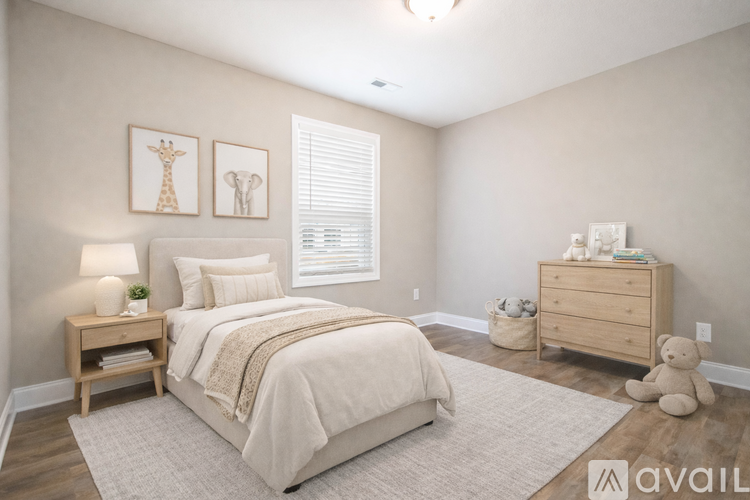 A bedroom with a large bed, a nightstand with a lamp, and a dresser with a teddy bear.