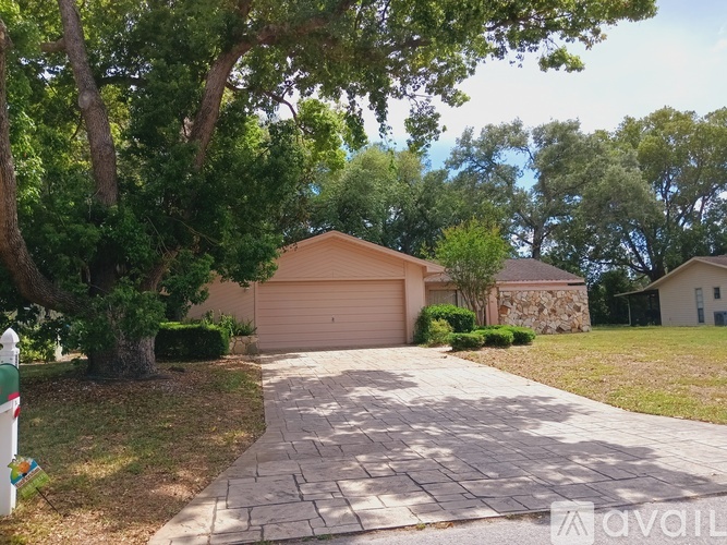 A house with a driveway and a garage is surrounded by trees.