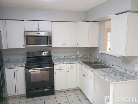 A kitchen with white cabinets and a black oven.