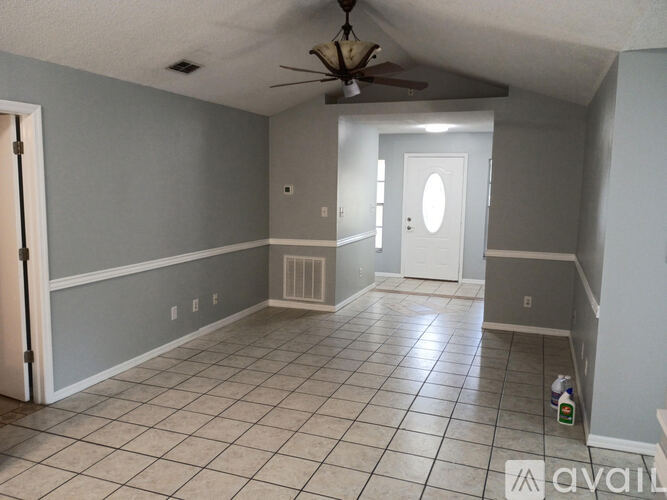 A room with a ceiling fan and tile flooring.