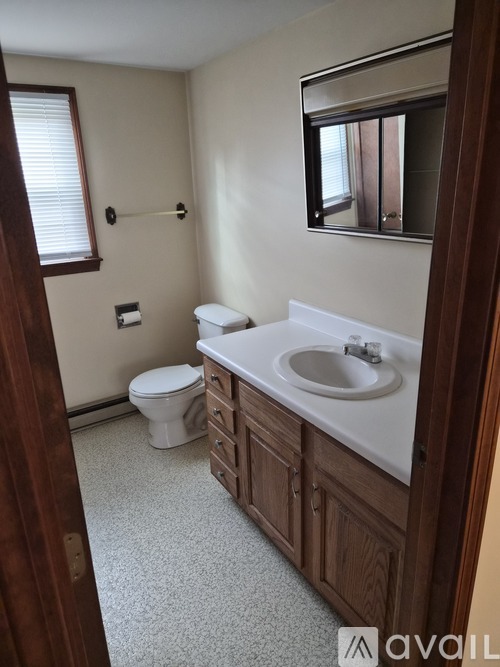 A bathroom with a toilet, sink, and mirror.
